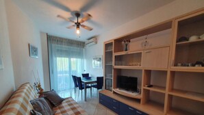 Un salón con sofá, televisor y estantería de madera.