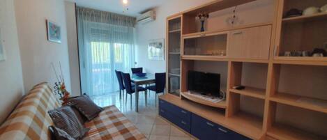 A living room with a sofa, TV, and wooden shelving unit.