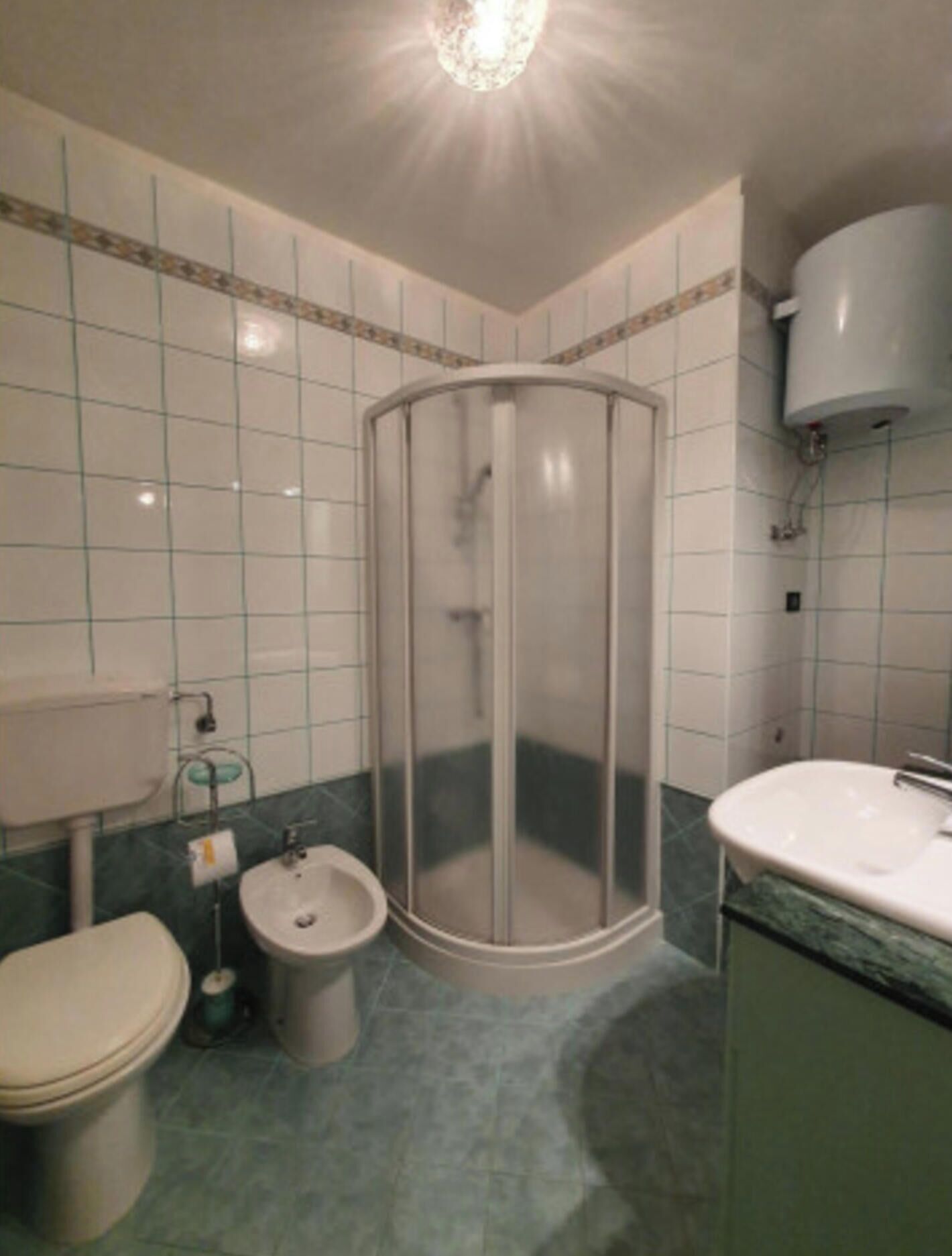 Un baño con inodoro, bidé, cabina de ducha y lavabo.