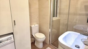 A bathroom with a toilet, a shower enclosure, a sink, and a washing machine.