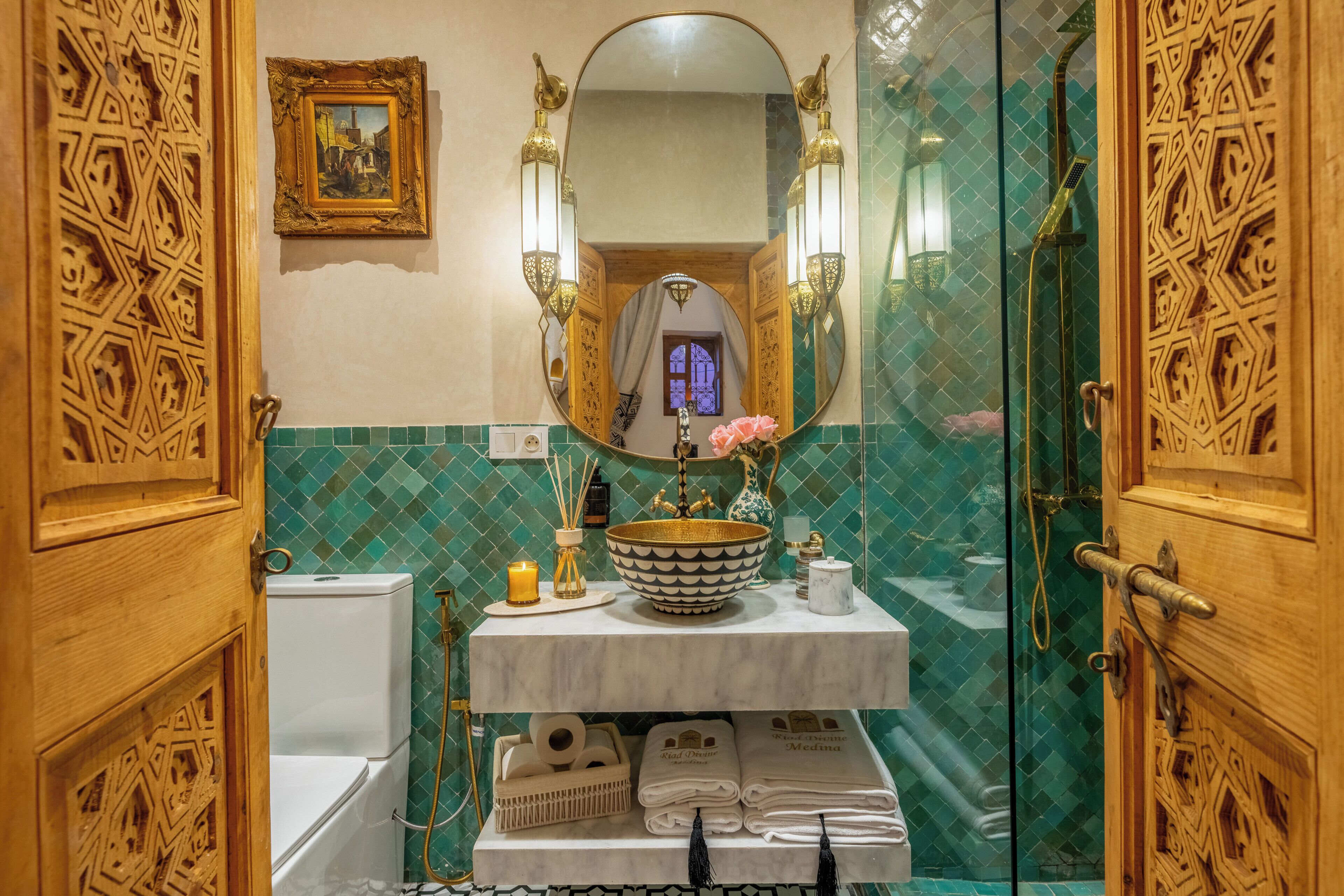 A bathroom with a marble sink, a mirror, a framed picture, and a shower with a glass door.