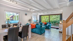 A spacious living area with a dining table, multiple sofas, and a staircase. - Holiday Home for 5 People (105 m²) in Südbrookmerland (Südbrookmerland)