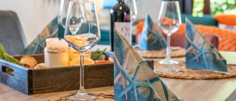 Une table à manger avec des sets de table, des verres à vin, des couverts et une bouteille de vin.