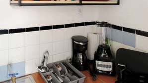 Eine Küche mit einer schwarzen Metallregalkonstruktion, auf der Töpfe und eine Kaffeemaschine stehen.
