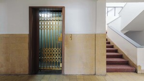 Eine Treppe mit Handlauf und einer Tür mit einem Metallgitter.