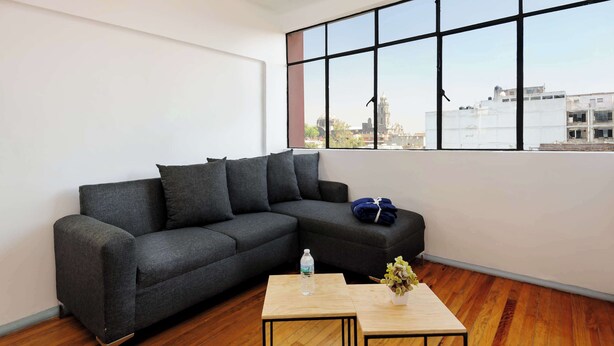 Ein modernes Wohnzimmer mit einer Eckcouch, einem Holztisch und einem großen Fenster mit Blick auf die Stadt.
