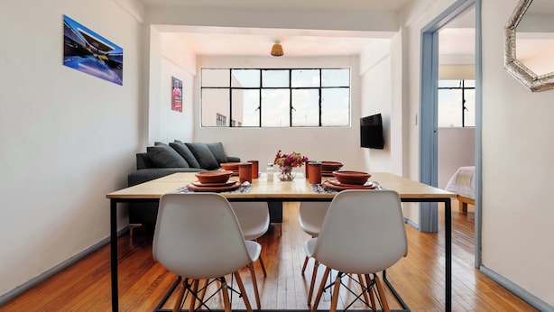 Un coin repas avec une table en bois, des chaises blanches et un canapé.