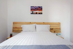 A neatly made bed with a wooden headboard, white bedding, and a small potted plant on the nightstand. - Edificio Aurora: Views & Vintage Charm (Centro)