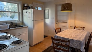 Una cocina con estufa, refrigerador, lavaplatos y una mesa de comedor con sillas.