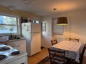 Una cocina con estufa, refrigerador, lavaplatos y una mesa de comedor con sillas.