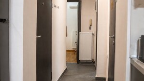 A narrow hallway with dark floor tiles, light-colored walls, and a ceiling light fixture. - D-Suites - Aristotelous Square Superior Apartment, Thessaloniki Centre (Thessaloniki)