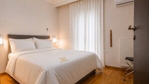 A hotel room with a bed, a radiator, a door, and a window with curtains. - D-Suites - Aristotelous Square Superior Apartment, Thessaloniki Centre (Thessaloniki)