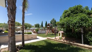 A backyard with a wooden swing set, a small playhouse, and a palm tree. - Apartment 'Casa Torre Di Specchio with Pool' – Wi-Fi and Air Conditioning (Bari)