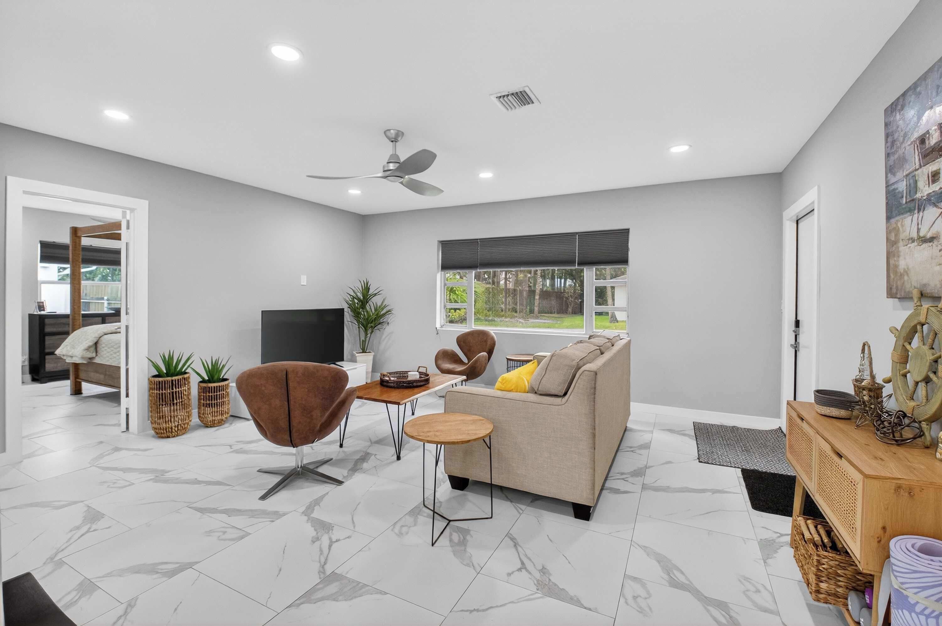 A modern living room with a sofa, armchair, coffee table, and a television.