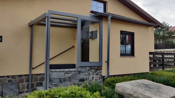 Uma casa com base de pedra, moldura de porta de metal e janela com cortina.