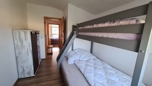 A bunk bed with a wooden ladder, a small table, and a wardrobe in a hallway. - Apartment 'Haus Rose 2' with Shared Garden, Balcony and Wi-Fi (Loddin)