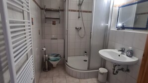 A bathroom with a shower, toilet, sink, and a mirror. - Apartment 'Haus Rose 2' with Shared Garden, Balcony and Wi-Fi (Loddin)