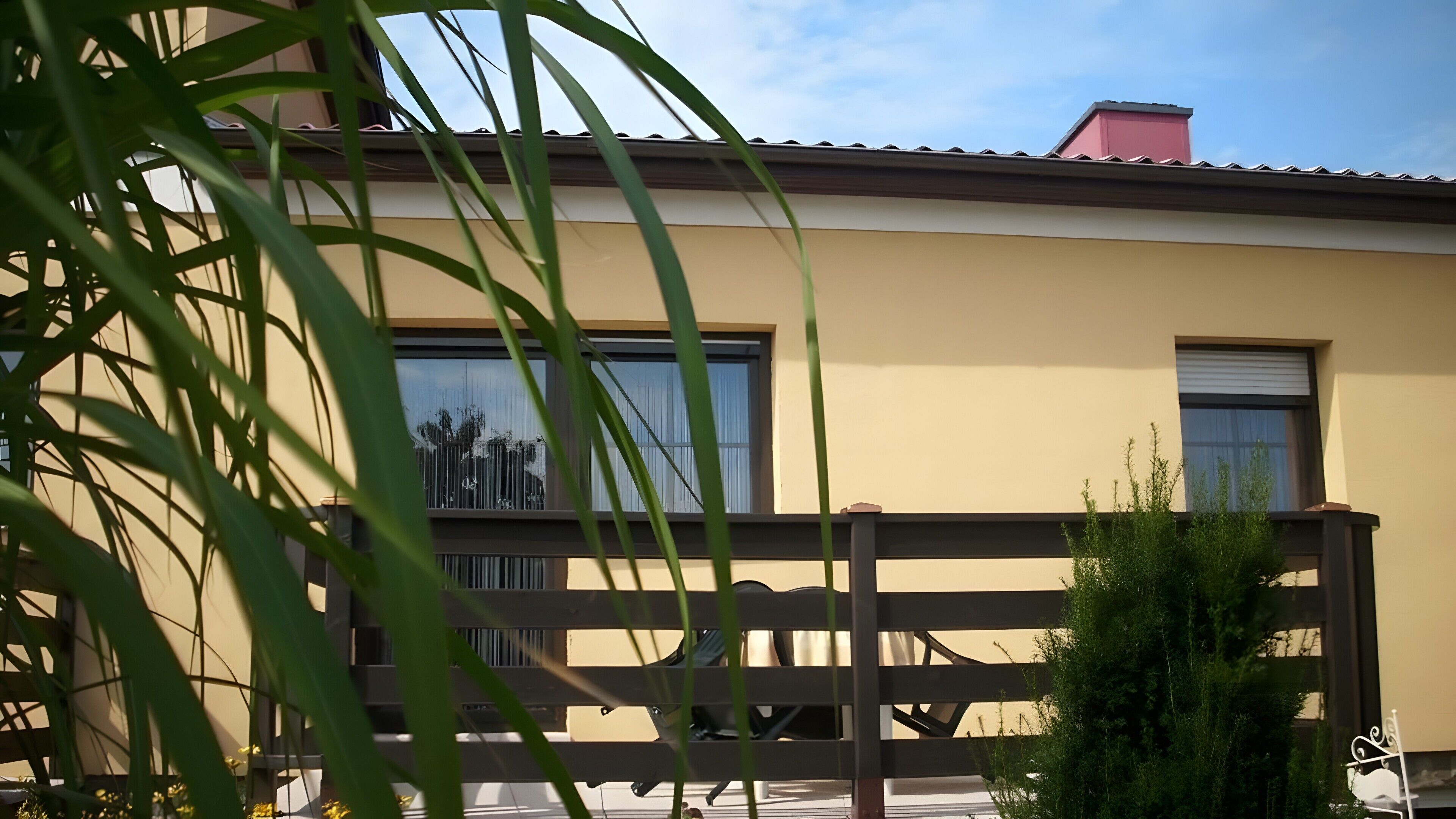 Ein modernes Gebäude mit großen Fenstern, einem Balkon und einem Zaun.