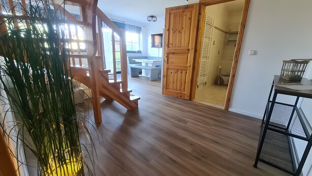 A wooden staircase leading to a balcony, a dining area with a bench, and a bathroom with a shower and toilet. - Apartment 'Haus Rose 2' with Shared Garden, Balcony and Wi-Fi (Loddin)