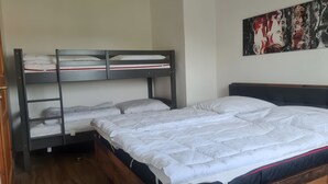 Un lit superposé à deux niveaux, avec un lit simple en bas et un tableau accroché au mur.