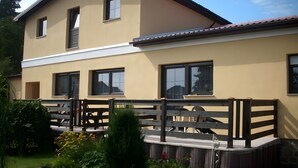 Un bâtiment à deux étages, doté de nombreuses fenêtres, d’un balcon et d’une clôture en bois.