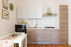 A compact kitchen with white cabinets, a gas stove, a sink, and a small countertop.