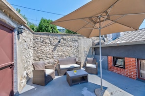 Een terras met wicker meubels, een tafel en een grote parasol.