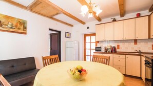 A cozy kitchen with wooden beams, a dining table with a fruit bowl, a sofa, and a microwave. - Charming vacation apartment with terrace & barbecue in quiet surroundings (Bribir)