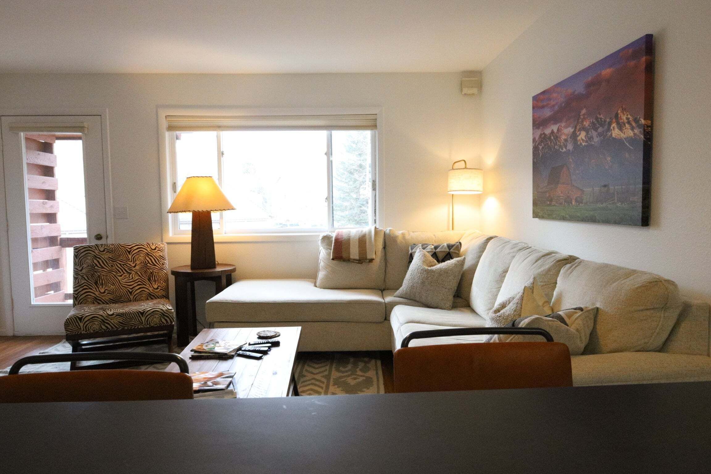 A living room with a sofa, armchairs, a coffee table, a lamp, and a painting on the wall.