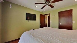 A bedroom with a bed, a ceiling fan, a television mounted on the wall, and two doors. - 1849 Condos 309 2 Bedroom Condo (Mammoth Lakes)