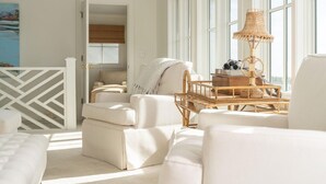 Una habitación bien iluminada con un amplio ventanal, una lámpara de mimbre y un sofá blanco.