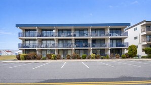 A multi-story hotel with balconies, a parking lot, and a clear sky. - Eldorado 2 1 Bedroom Condo (Ocean City)
