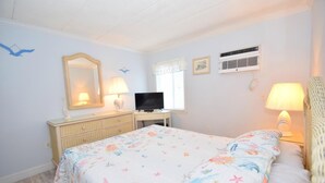 A bedroom with a bed, dresser, television, and two wall-mounted air conditioners. - Eldorado 2 1 Bedroom Condo (Ocean City)