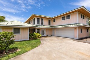 Ein zweistöckiges Haus mit Garage, überdachter Auffahrt und gepflegtem Rasen.