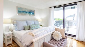A bedroom with a bed, bedside table, bench, and a view of the outside. - Oceanfront Penthouse w/ Outdoor Balconies, Community Pool, Beach Access, Playground & Kid's Pool (Isle of Palms)