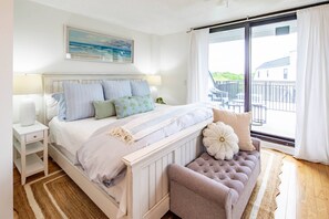 Een slaapkamer met een bed, nachtkastje, bankje en uitzicht.