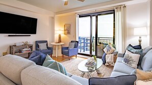 A living room with a sofa, armchairs, a coffee table, a TV, a ceiling fan, and a balcony with a view. - Oceanfront Penthouse w/ Outdoor Balconies, Community Pool, Beach Access, Playground & Kid's Pool (Isle of Palms)