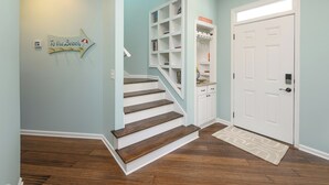 A staircase leading to a landing with a 'To the Beach' sign, a white door, and a built-in bookshelf. - 4 BR Beach House with a Private Pool! Beach Life (Surfside Beach)