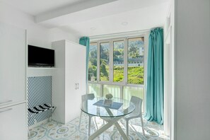 Una cocina moderna con televisión, una mesa de vidrio y vistas al verdor exterior.