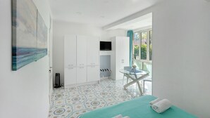 Ein Zimmer mit Bett, kleinem Tisch, Fernseher und Fenster.