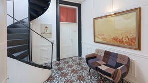 A staircase with a black handrail, a white door, a patterned floor, and a framed painting on the wall. - Apartment 'La Finestra' with Sea View, Wi-Fi and Air Conditioning (Castellammare di Stabia)