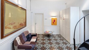 A hallway with patterned flooring, a sofa, a painting, and a staircase. - Apartment 'La Libreria' with Mountain View, Wi-Fi and Air Conditioning (Castellammare di Stabia)