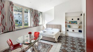 A bedroom with a bed, a glass table with chairs, a bookshelf, and a window with curtains. - Apartment 'La Libreria' with Mountain View, Wi-Fi and Air Conditioning (Castellammare di Stabia)