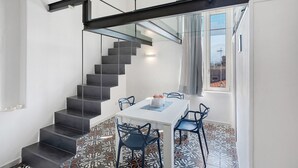 Un interno moderno con una scala, una zona pranzo con sedie e pavimento decorato.
