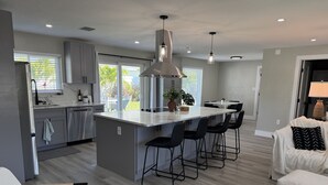 Eine moderne Küche mit Kochinsel, Barhocker und Essbereich mit Tisch und Stühlen.