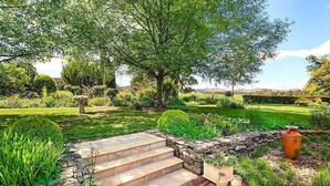 Ein Garten mit einer Steintreppe, einer Holzterrasse und einem großen Baum.