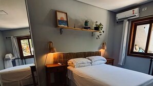 A bedroom with a bed, bedside tables, a mirror, a shelf with plants, and a window. - Studio | 5 min from airport | 100 m from beach | Beto Carrero World (Navegantes)