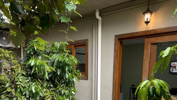 A courtyard with a tiled floor, a large tree, and a door with a window. - Studio | 5 min from airport | 100 m from beach | Beto Carrero World (Navegantes)