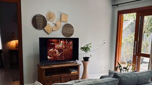 A modern living room with a television, grey sofa, and decorative wall art. - Studio | 5 min from airport | 100 m from beach | Beto Carrero World (Navegantes)