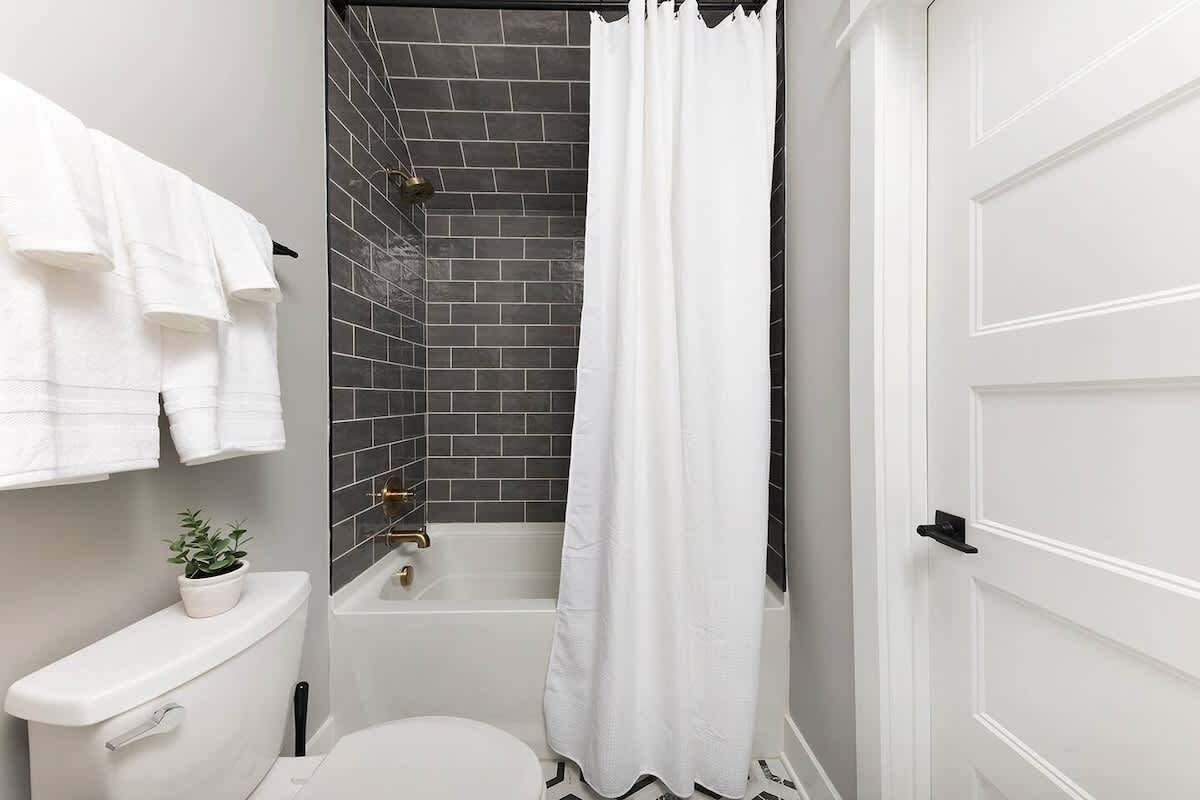 A bathroom with a toilet, a shower with a curtain, and a sink.